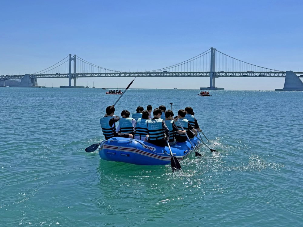 광안대교를 배경으로 래프팅 보트를 타는 사람들